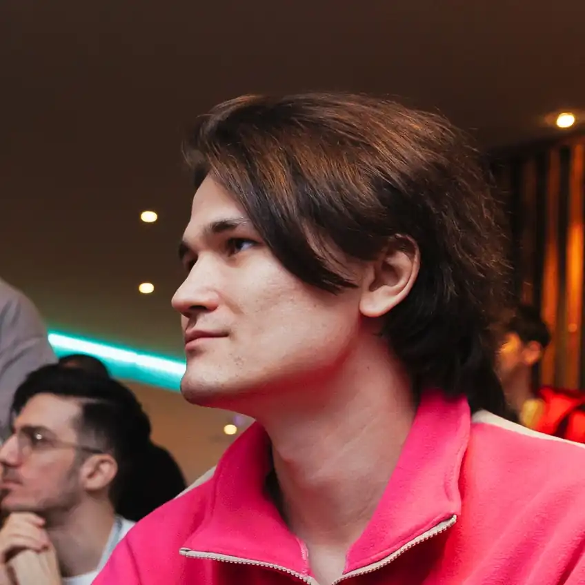 Молодой человек в розово-бежевой кофте, он смотрит влево